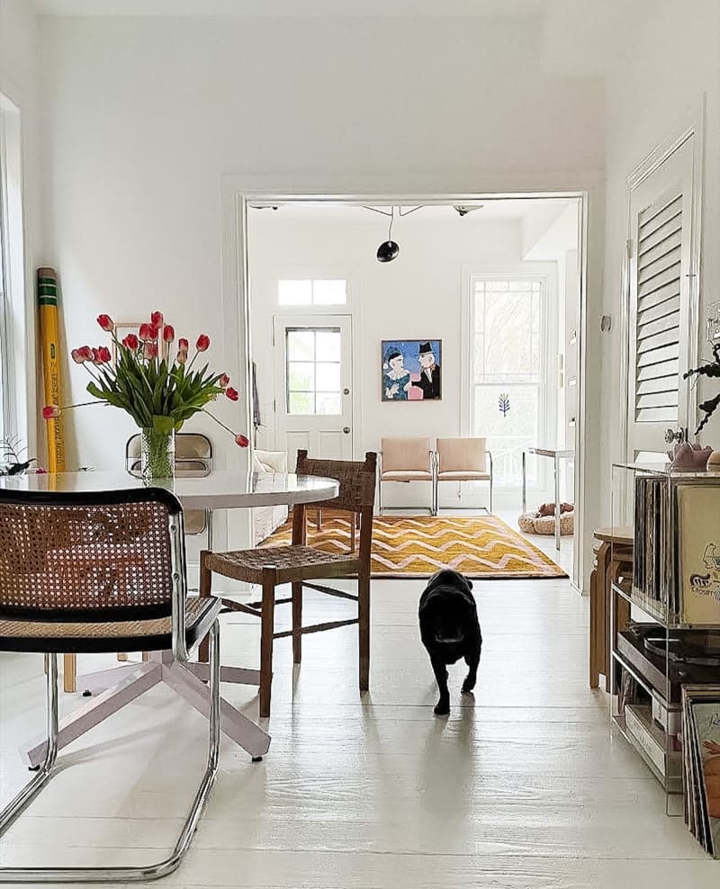 Dog running through living room with large pencil sculpture in the corner.