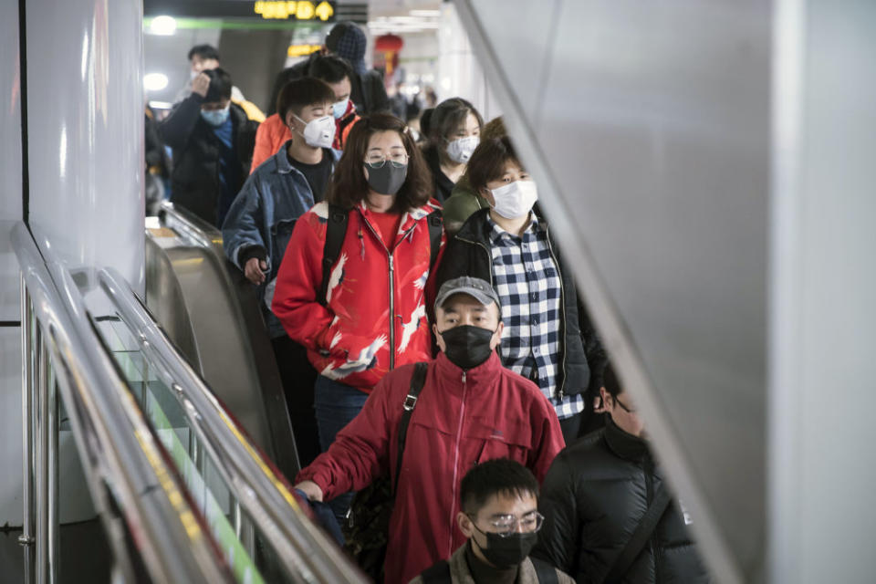 Travelers wear protective masks while moving through a subway station before Chinese New Year in Shanghai. Source: Getty