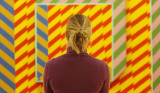 A woman looking at an artwork by Derek Boshier 