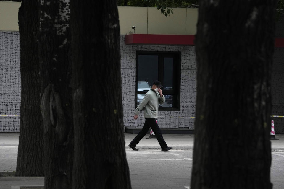 A man wearing a mask walks to a line for COVID test, Wednesday, April 27, 2022, in Beijing. Workers put up fencing and police restricted who could leave a locked-down area in Beijing on Tuesday as authorities in the Chinese capital stepped up efforts to prevent a major COVID-19 outbreak like the one that has all but shut down the city of Shanghai. (AP Photo/Ng Han Guan)