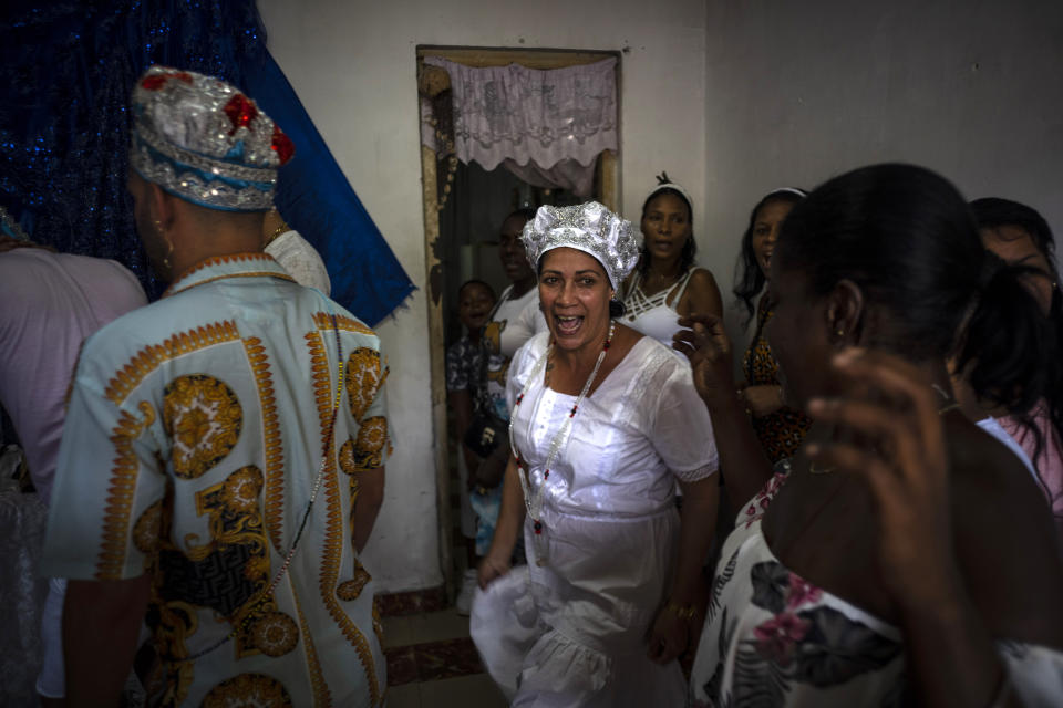 Maritza de la Rosa Perdomo, center, dances before a blue altar during a Santería ceremony in Havana, Cuba, Sunday, Nov. 13, 2022. Perdomo, family and friends make offerings at the altar. In exchange, they ask for good health, strength during hardship, and even luck in love. (AP Photo/Ramon Espinosa)