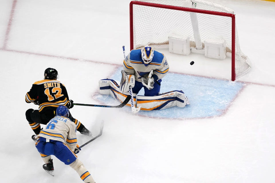 St. Louis Blues goaltender Ville Husso deflects a shot by Boston Bruins' Craig Smith (12) as Blues' Marco Scandella (6) defends during the second period of an NHL hockey game Tuesday, April 19, 2022, in St. Louis. (AP Photo/Jeff Roberson)