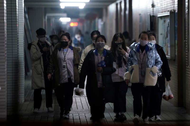 Workers wearing masks walk outside their dormitory, in an electronics manufacturing factory in Shanghai