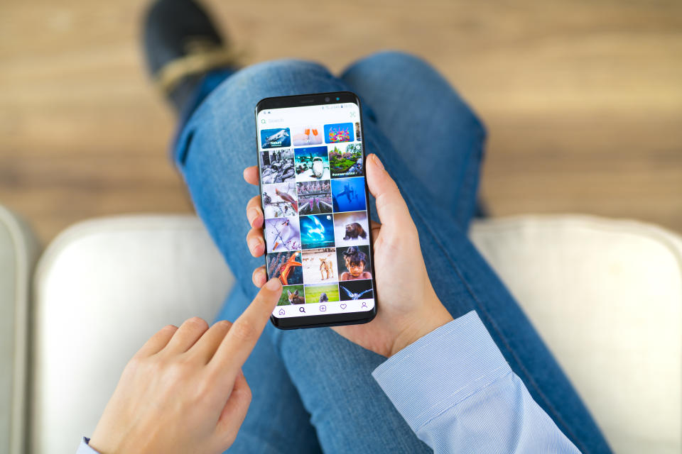 İstanbul, Turkey - February 10, 2019: Woman using smart phone on a couch. The smart phone is an iPhone 8 displaying Instagram application.  iPhone is a touchscreen smartphone developed by Apple Inc.