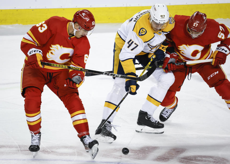 Nashville Predators forward Michael McCarron, center, is checked by Calgary Flames forward Adam Ruzicka, left, and defenseman Nick DeSimone during the first period of an NHL hockey game in Calgary, Alberta, Tuesday, Nov. 7, 2023. (Jeff McIntosh/The Canadian Press via AP)