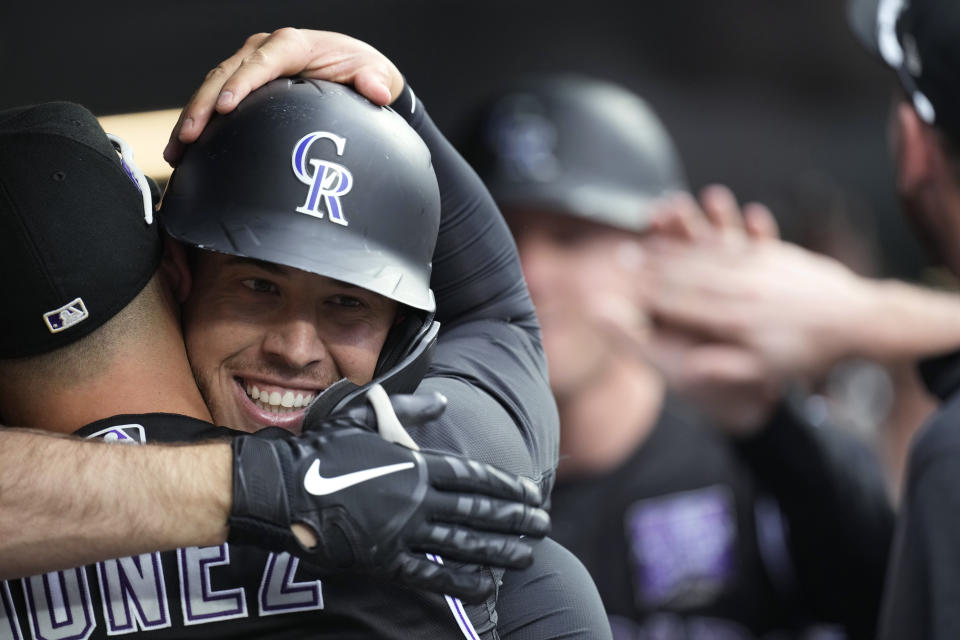 Colorado Rockies' Dom Nunez, left, hugs C.J. Cron, who returns to the dugout after hitting a grand slam off Milwaukee Brewers starting pitcher Brandon Woodruff during the first inning of a baseball game Thursday, June 17, 2021, in Denver. (AP Photo/David Zalubowski)