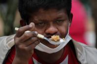 Wearing a mask to curb the spread of the new coronavirus, Delio Carballo Martinez, who is unemployed, eats "guiso" at a soup kitchen during a protest by organizations that are feeding the poor, in downtown Asuncion, Paraguay, Monday, Sept.21, 2020. Organizations are demanding that the government begin to provide funds that will help them with their efforts to provide meals for the poor. (AP Photo/Jorge Saenz)