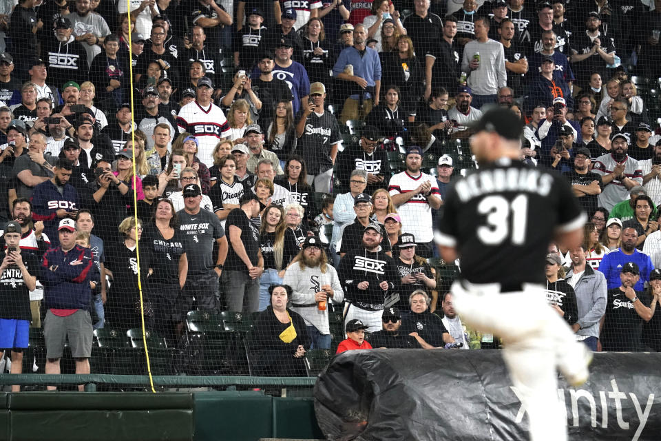 FILE - In this Saturday, Oct. 2, 2021, file photo, fans stand as they watch Chicago White Sox relief pitcher Liam Hendriks work during the ninth inning of a baseball game against the Detroit Tigers in Chicago. The White Sox have a rare opportunity to capture the spotlight and expand their fan base in a city where they're often overshadowed by their neighbors a few miles north. They're in the playoffs for the second year in a row, a first for the charter American League franchise, after running away with the Central division. (AP Photo/Nam Y. Huh, File)