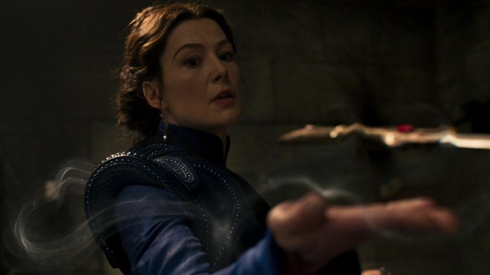 A close-up shot of Moiraine, her hand stretched forth holding the cursed ruby dagger with flows of air. Her expression is one of both astonishment and terror