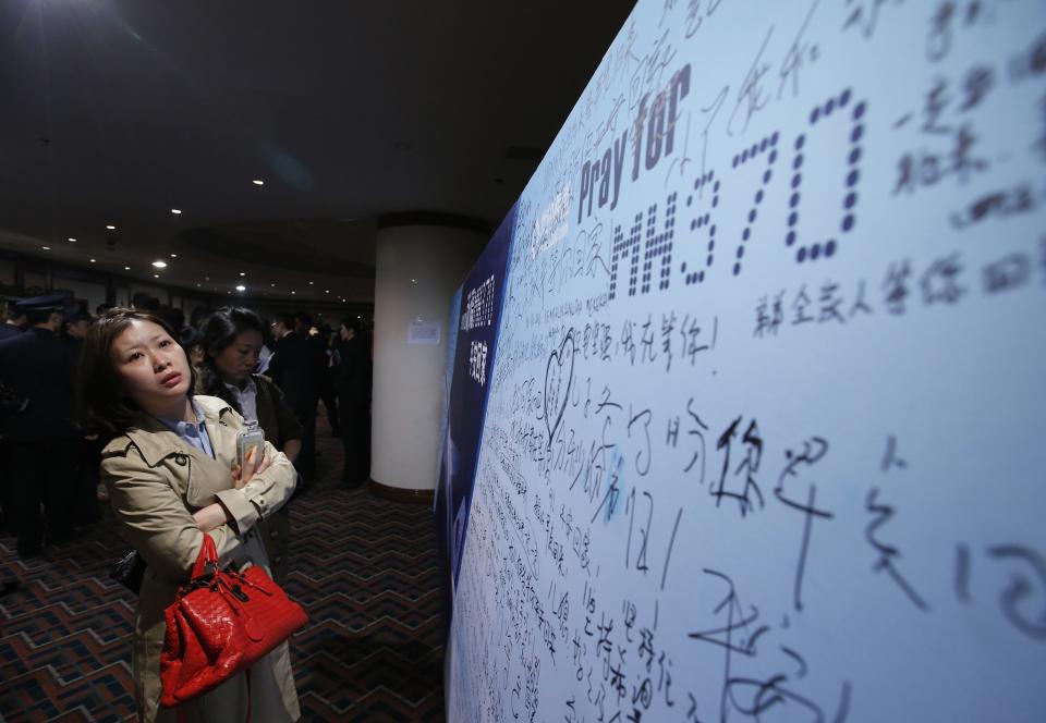 A female journalist looks at a message board with messages wishing the return of passengers aboard Malaysia Airlines flight MH370 at the Lido Hotel in Beijing