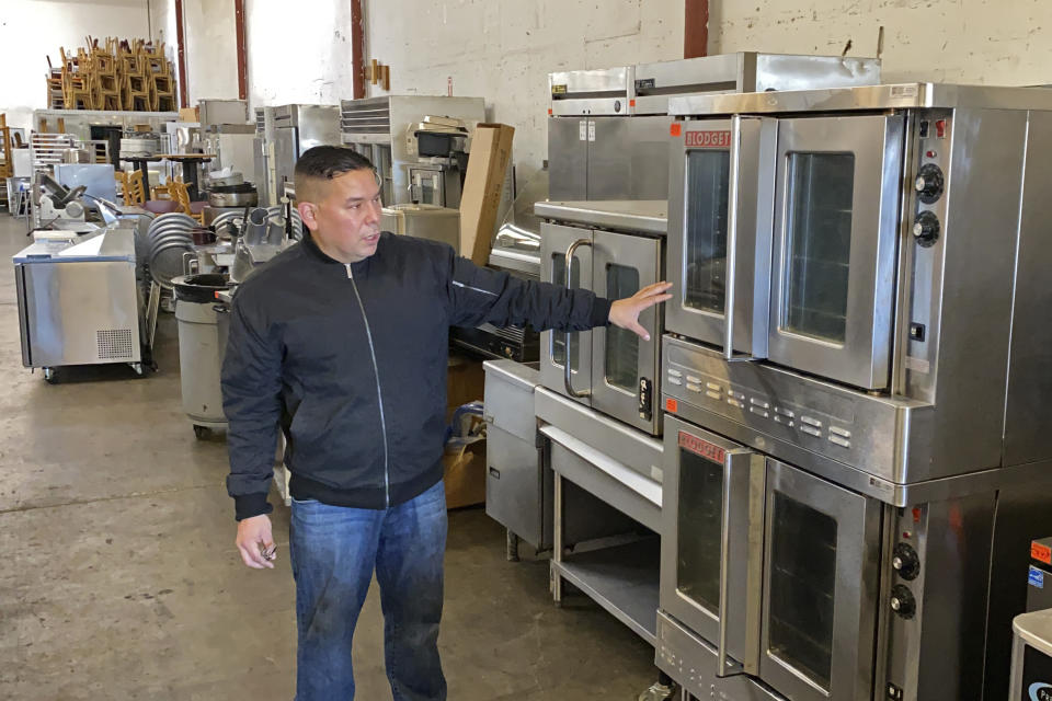 Jose Bonilla Jr. shows a used industrial oven for sale in the warehouse of his family's business, American Restaurant Supply in San Leandro, Calif., on Jan. 14, 2021. The pandemic has forced thousands of restaurants to permanently shut their doors as dining restrictions keep customers away. But the unprecedented closures have created a business boom for commercial auctioneers that buy and sell used restaurant equipment. (AP Photo/Terry Chea)