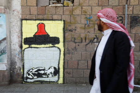 A man walks pass a graffiti by artist Thi Yazen AL-Alawy depicting a bottle of milk with a malnourished child inside along a street in Sanaa, Yemen, October 20, 2016. REUTERS/Mohamed al-Sayaghi
