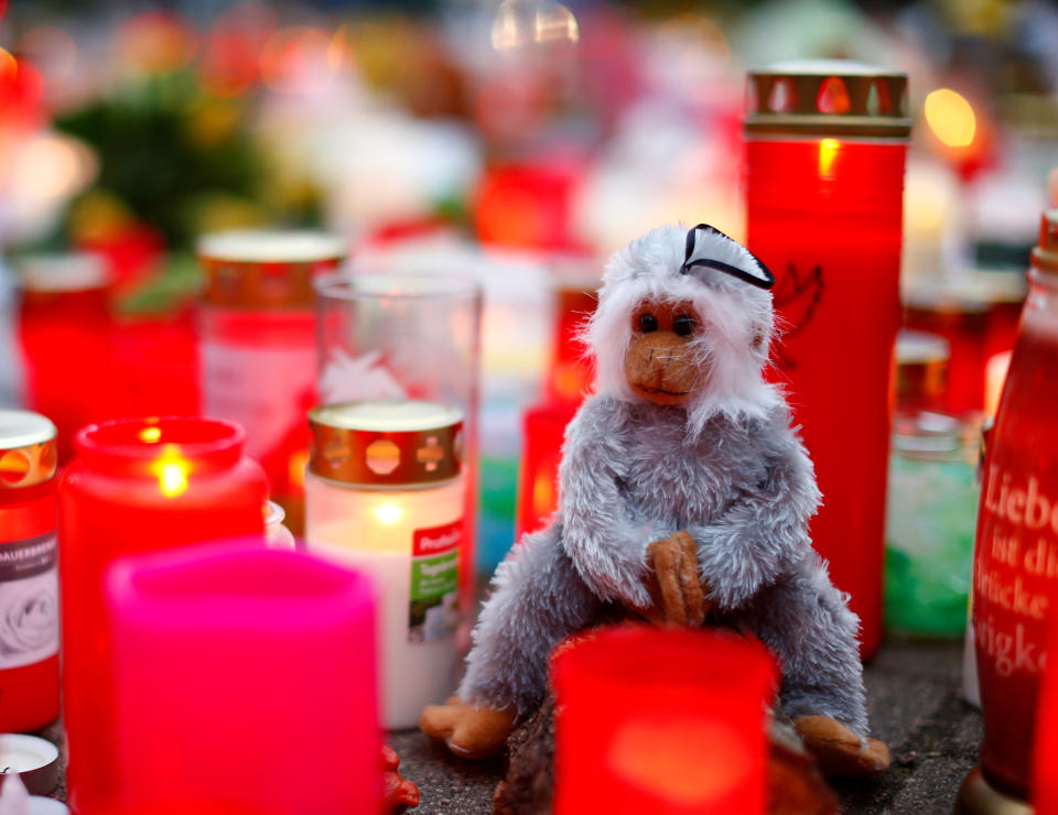 A toy monkey is seen between flowers and candles outside the zoo of Krefeld after a monkey house burned down and dozens of animals were killed by the fire in Krefeld, Germany, January 2, 2020. REUTERS/Thilo Schmuelgen     TPX IMAGES OF THE DAY