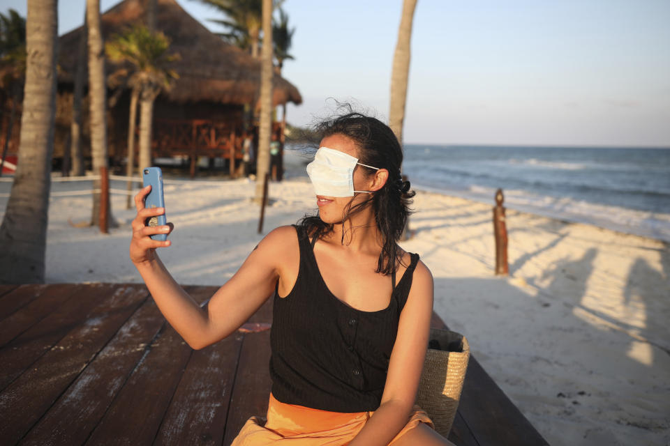 Mexico City resident Romina Montoya takes a playful selfie wearing a protective face mask over her eyes and nose, in Playa del Carmen, Quintana Roo state, Mexico, Wednesday, Jan. 6, 2021. Concern is spreading that the critical winter holiday tourism success could be fleeting because it came as COVID-19 infections in both Mexico and the United States were reaching new heights. (AP Photo/Emilio Espejel)