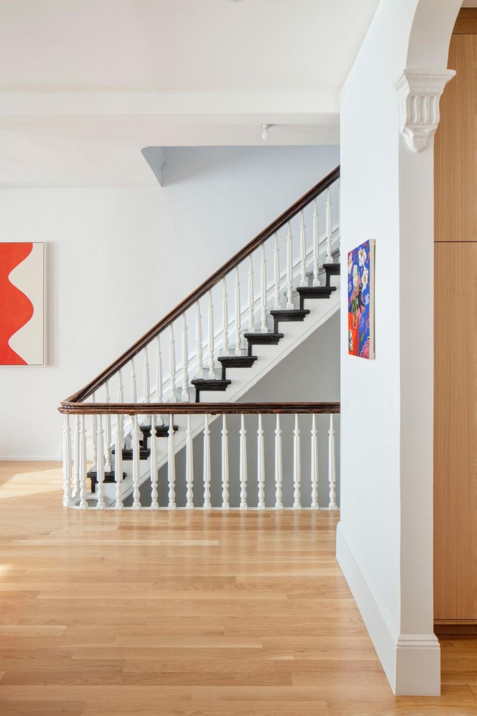 The refinished stairs are a key element to the open floor plan. The painting in the foreground is by Nikki Maloof.