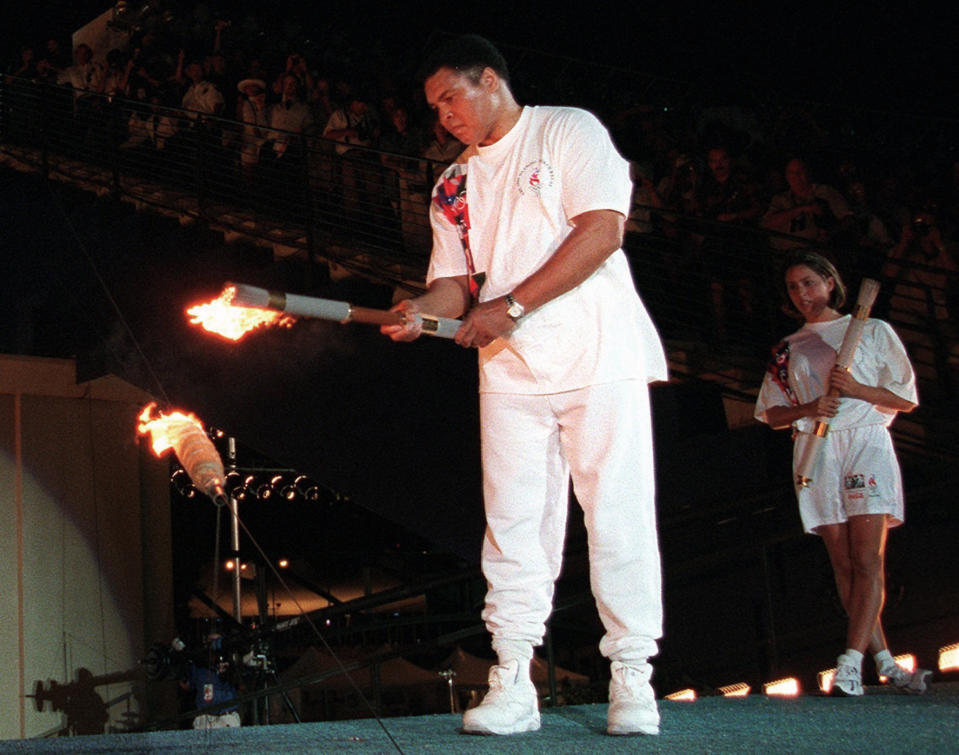 FILE - In this July 19, 1996, file photo, American swimmer Janet Evans , right, looks on as Muhammad Ali lights the Olympic flame during the 1996 Summer Olympic Games opening ceremony in Atlanta. (AP Photo/Michael Probst, File)