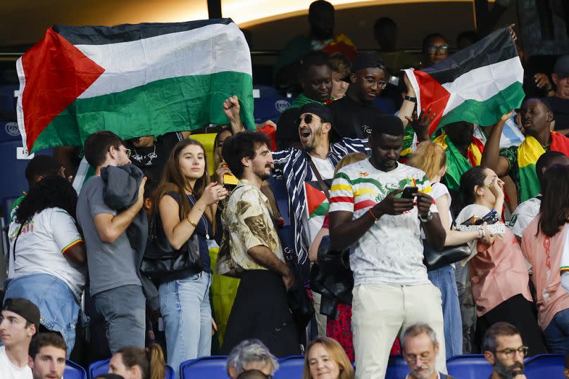 Aficionados al fútbol sostienen banderas palestinas durante el partido Israel-Malí