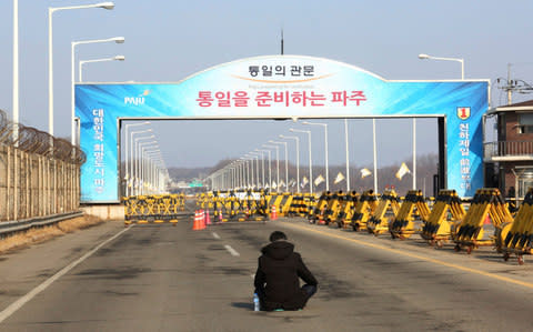 A family member of victims of the sunken South Korean naval ship Cheonan by a North Korean attack sits on a road to protest against a visit of Kim Yong Chol - Credit: AP