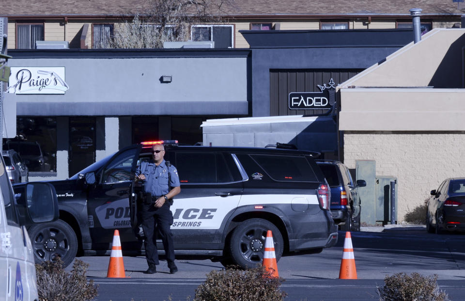 A police officer exits his car near a crime scene at a gay nightclub in Colorado Springs, Colo., Sunday, Nov. 20, 2022 where a shooting occurred late Saturday night. (AP Photo/Geneva Heffernan)