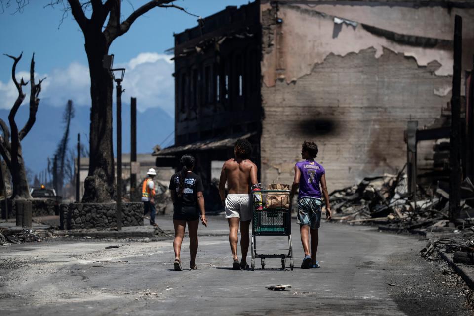 Residents push a cart amid the ruins left by a wildfire.