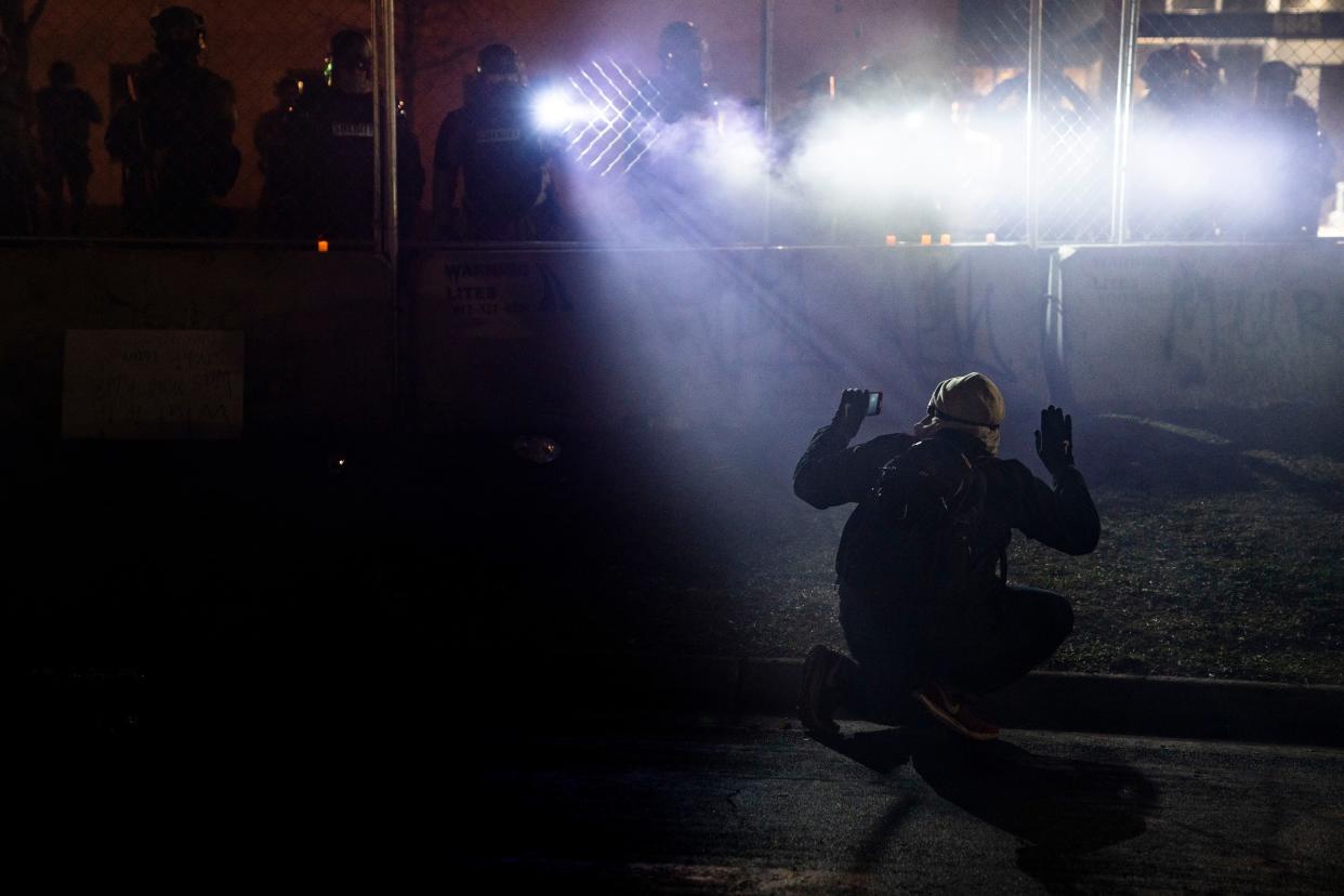 Police shine lights on demonstrator with raised hands during a protest over Sunday's fatal shooting of Daunte Wright outside the Brooklyn Center Police Department on Wednesday, April 14, 2021, in Brooklyn Center, Minn.