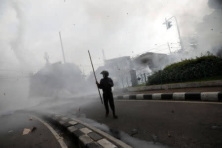 A man walks as the river water is being sprayed from a helicopter towards the protesters during a protest following the announcement of last month's election official results in Jakarta, Indonesia, May 22, 2019. REUTERS/Willy Kurniawan