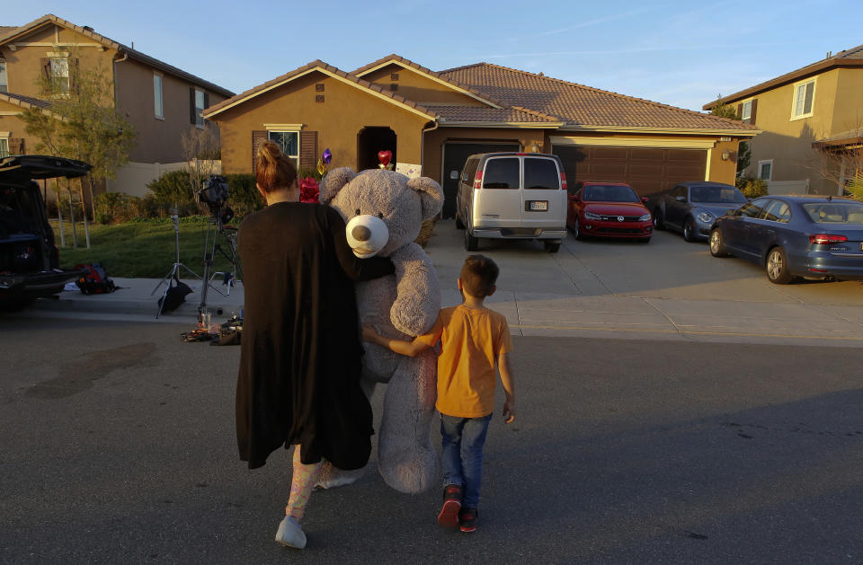 FILE - In this Jan. 18, 2018, file photo, neighbor Avery Sanchez walks with his mother, Liza Tozier, to drop off his large "Teddy" as a gift for the children who lived in a home where police arrested a couple on accused of holding 13 children captive in Perris, Calif. Jack Osborn, an attorney for seven adult children who were freed from the California home and years of alleged abuse says they are not bitter. Osborn said in an interview aired Wednesday, Jan. 16, 2019, on "Today" that his clients want people to know they are survivors. The Turpins have pleaded not guilty to the charges. (AP Photo/Damian Dovarganes, File)