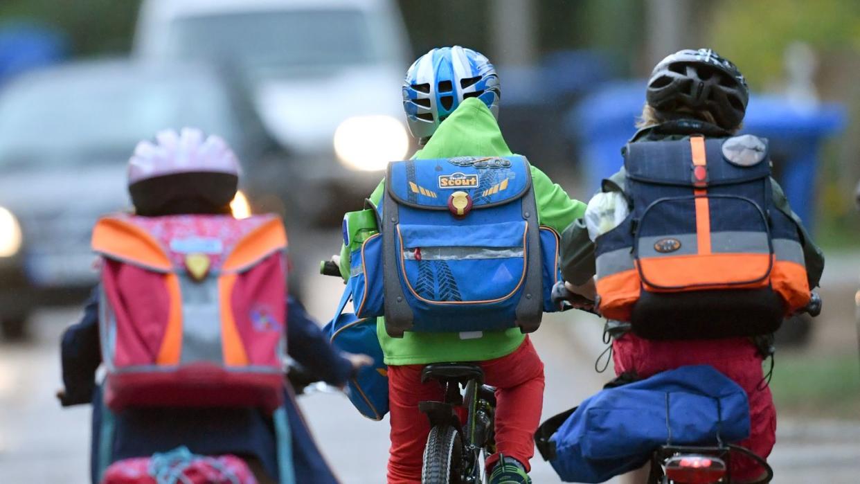Kinder sind auf einer Straße mit dem Fahrrad unterwegs zur Schule. Symbolbild