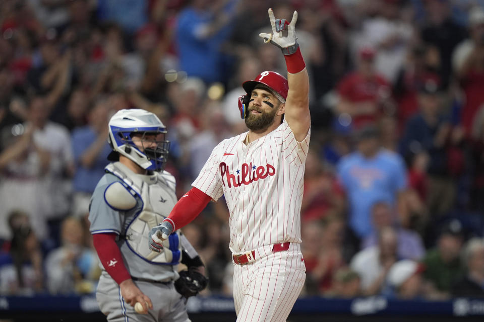 Philadelphia Phillies' Bryce Harper, right, reacts past Toronto Blue Jays catcher Alejandro Kirk after hitting a grand slam during the fourth inning of a baseball game, Tuesday, May 7, 2024, in Philadelphia. (AP Photo/Matt Slocum)