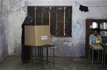 A woman casts her vote inside a booth as a polling officer (R) watches at a polling station in Amroha in the northern Indian state of Uttar Pradesh April 17, 2014. REUTERS/Adnan Abidi