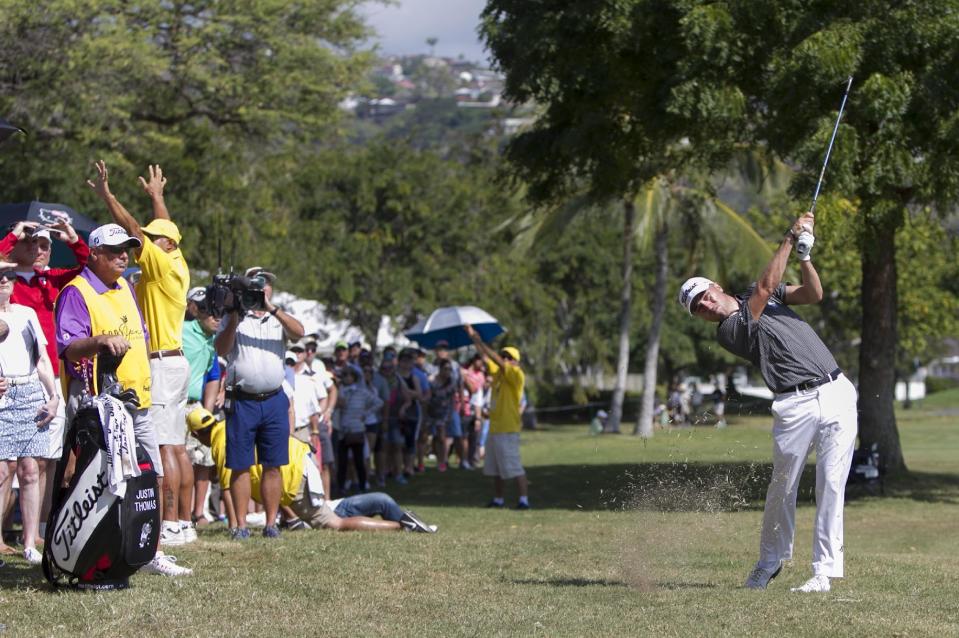 As the gallery watches, Justin Thomas hits off the rough on the third fairway during the final round of the Sony Open golf tournament, Sunday, Jan. 15, 2017, in Honolulu. (AP Photo/Marco Garcia)