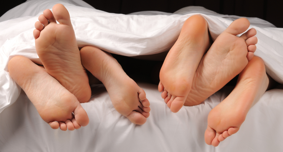 People's legs visible from under a duvet. 