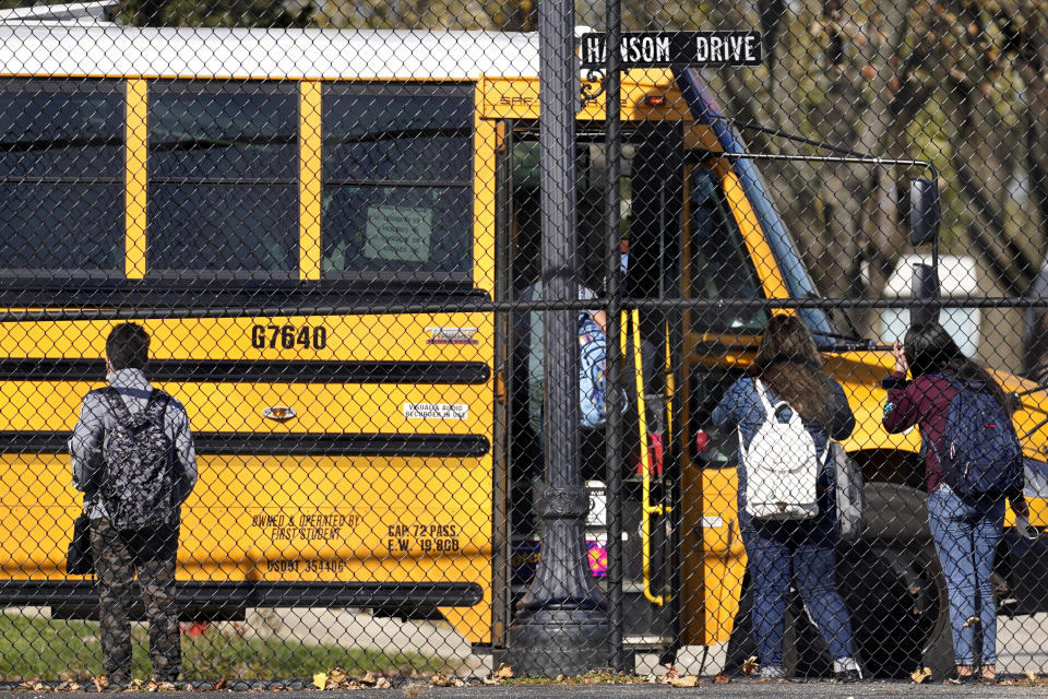 FILE - In this Friday, Nov. 6, 2020 file photo, students wait to board a school bus in Wheeling, Ill. With COVID-19 infections and hospitalizations spiking to record numbers across the U.S. and abroad, many school districts are temporarily shutting down in-person classes as holidays loom. (AP Photo/Nam Y. Huh)