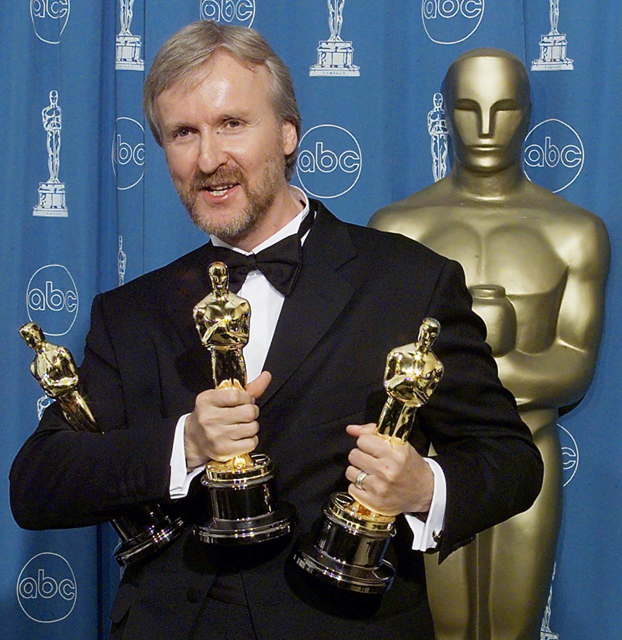 LOS ANGELES, UNITED STATES:  James Cameron holds the three Oscars he won for Best Fim, Best Director, and Best Editing 23 March at the 70th Annual Academy Awards at the Shrine Auditorium in Los Angeles.   (ELECTRONIC IMAGE)    AFP PHOTO/Hector MATA (Photo credit should read HECTOR MATA/AFP via Getty Images)