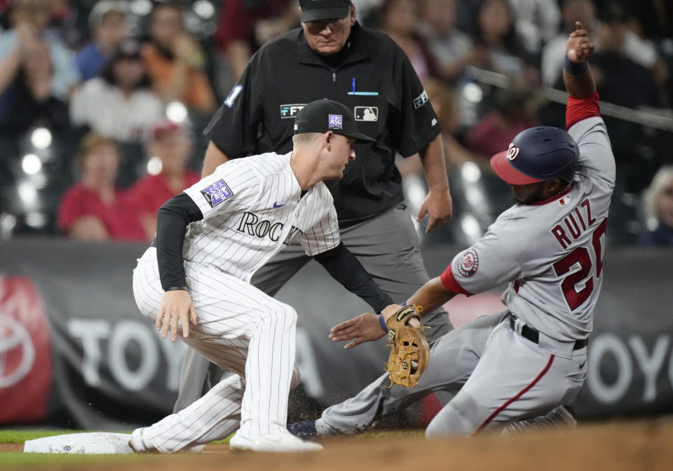 Colorado Rockies third baseman Ryan McMahon, left, tags out Washington Nationals' Keibert Ruiz as he tries to advance from first to third base on a single hit by Luis Garcia in the fourth inning of a baseball game Monday, Sept. 27, 2021, in Denver. (AP Photo/David Zalubowski)