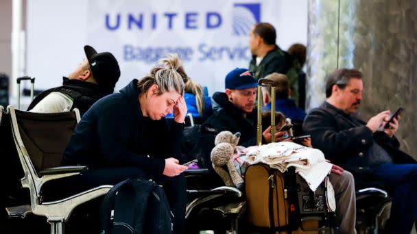 PHOTO: People sit at Denver International Airport amidst a wave of flight cancelations due to a winter storm, Feb. 22, 2023, in Denver. (Michael Ciaglo/Getty Images)