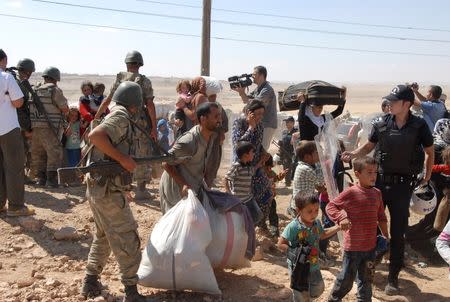 Syrian Kurds cross the border fence into Turkey near the southeastern town of Suruc in Sanliurfa province, September 19, 2014. REUTERS/Stringer