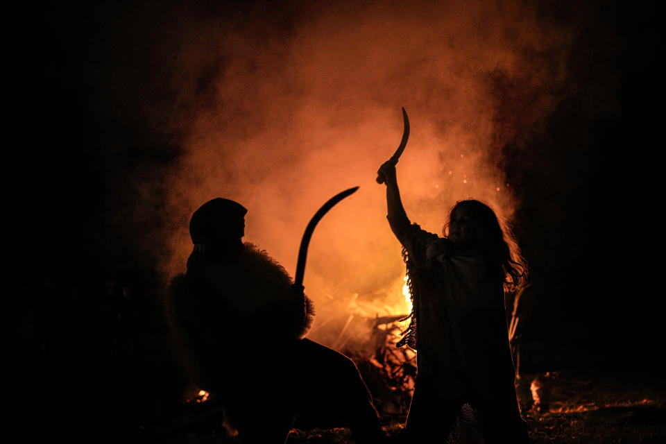 Children engage in a sword fight, backdropped by a campfire, during the Romula Fest historic reenactment festival in the village of Resca, Romania, Saturday, Sept. 3, 2022. (AP Photo/Andreea Alexandru)