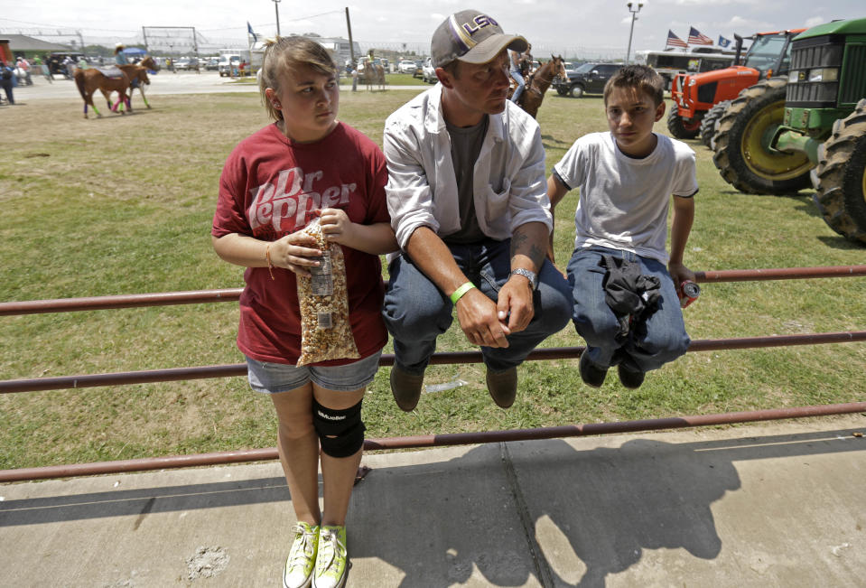 Inmate Jonah Maynard sits with his niece Raylin Maynard, 15, and Jacob Campbell, 12, at the Angola Prison Rodeo in Angola, La., Saturday, April 26, 2014. Louisiana’s most violent criminals, many serving life sentences for murder, are the stars of the Angola Prison Rodeo, the nation’s longest-running prison rodeo that this year celebrates 50 years. The event has grown from a small “fun” event for prisoners into big business, with proceeds going into the Louisiana State Penitentiary Inmate Welfare Fund for inmate education and recreational supplies. (AP Photo/Gerald Herbert)