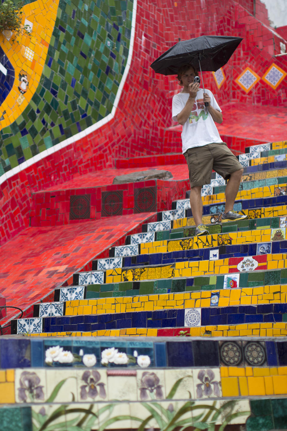 Tourist from Germany take photos on a stairway that was decorated by Chilean artist Jorge Selaron, which he titled the "Selaron Stairway" in Rio de Janeiro, Brazil, Thursday, Jan. 10, 2013. Selaron, an eccentric Chilean artist and longtime Rio resident who created a massive, colorful tile stairway in the bohemian Lapa district that's popular with tourists, was found dead on the stairway on Thursday. He was 54. Authorities are investigating the cause of death. (AP Photo/Felipe Dana)