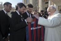 Pope Francis (R) holds a jersey of Argentine soccer team San Lorenzo, given to him as a gift from members of the team, during the Wednesday general audience in St Peter's Square at the Vatican December 18, 2013. REUTERS/Osservatore Romano