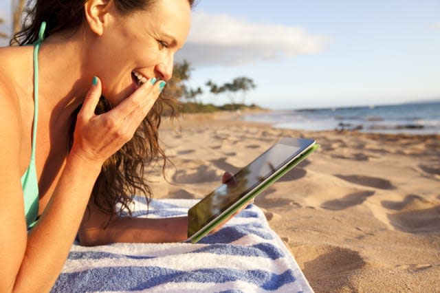 Female using a digital tablet at the beach.