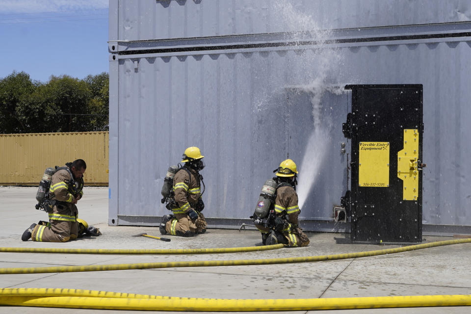 Cadets, who were formerly-incarcerated firefighters, train a simulated forceful entry of a structure fire at the Ventura Training Center (VTC) during an open house media demonstration Thursday, July 14, 2022, in Camarillo, Calif. California has a first-in-the nation law and a $30 million training program both aimed at trying to help former inmate firefighters turn pro after they are released from prison. The 18-month program is run by Cal Fire, the California Conservation Corps, the state corrections department and the nonprofit Anti-Recidivism Coalition at the Ventura Training Center northwest of Los Angeles. (AP Photo/Damian Dovarganes)