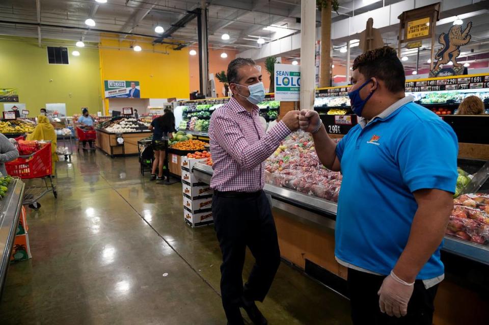 Sean Loloee, then a candidate for Sacramento City Council 2, fist bumps an employee at his Viva Supermarket in Sacramento’s Del Paso Heights neighorhood in 2020.