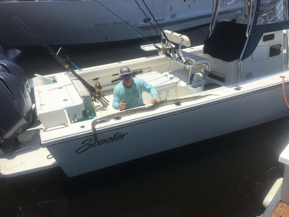 Charter captain Stephen Iannotta poses with that Burmese python that he spotted Thursday while boating in Naples Bay.