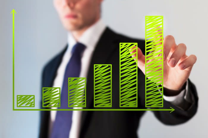 A man touches the tallest column on a chart showing growth.