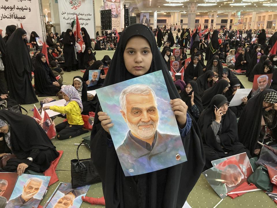 An Iranian girl holds up a portrait of the late Revolutionary Guard Gen. Qassem Soleimani, who was killed in a U.S drone attack in 2020 in Iraq, during a ceremony commemorating his death anniversary, at the Imam Khomeini grand mosque in Tehran, Iran, Wednesday, Jan. 3, 2024. Iran says bomb blasts at an event in the city of Kerman, honoring a prominent Iranian general slain in a U.S. airstrike in 2020, have killed at least 103 people and wounded 188 others. (AP Photo/Vahid Salemi)