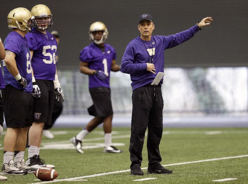 New Washington head football coach Chris Petersen, right, gives directions to his team on the first day of spring NCAA college football practice, Tuesday, March 4, 2014, in Seattle. (AP Photo/Ted S. Warren)