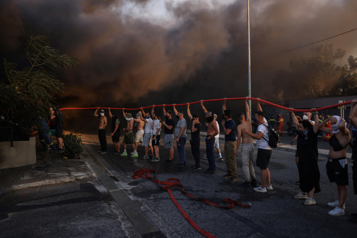 Volunteers and firefighters try to extinguish a fire in a building in Vrilissia, near Athens, on Monday. 