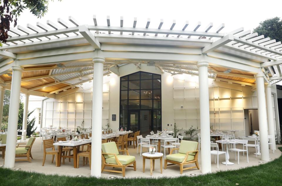 tables and chairs on an outdoor patio under a white and copper roof